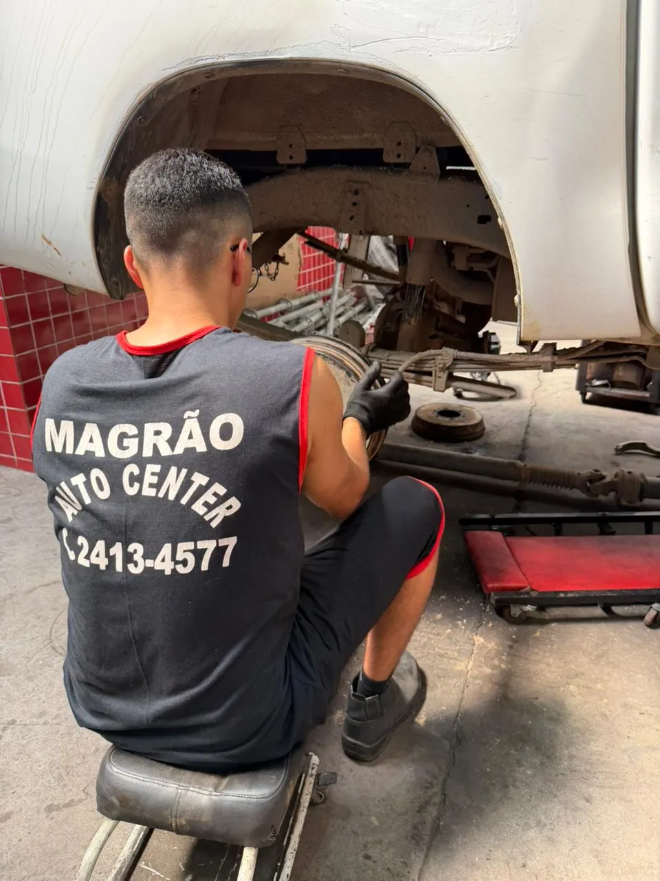 Mecânico da Magrão Auto Center realizando reparo de suspensão em veículo elevado em Campo Grande, RJ